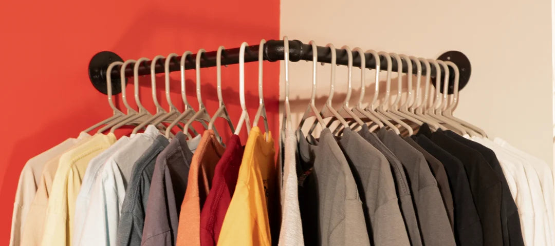 Clothing rack with various colored shirts against a red and beige background